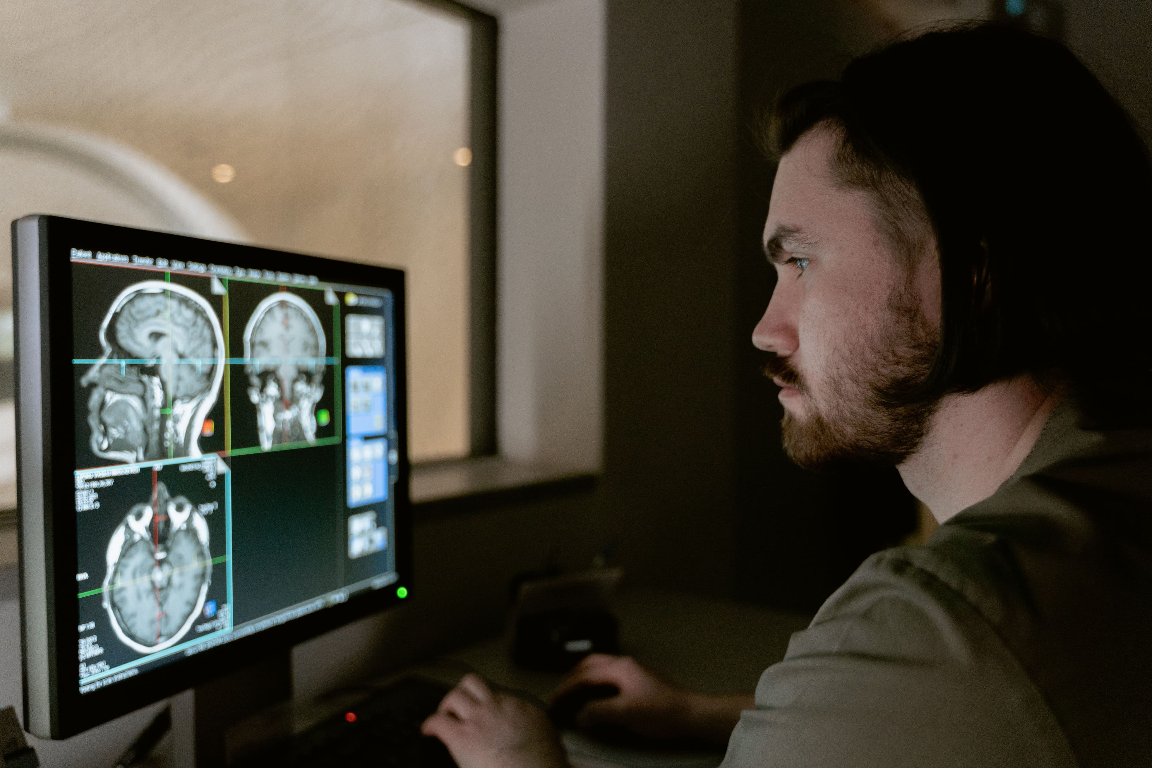 A clinician studying brain MRI scans on a monitor while engaged in research and ongoing learning